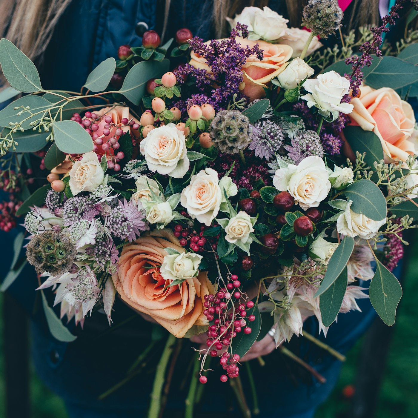 A hand-tied garden bouquet with cream roses, eucalyptus and seasonal berries